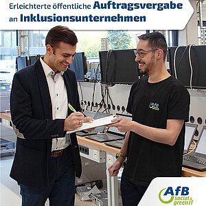 Two men are standing in the production area at AfB. The man on the left is wearing a jacket and signing a form. The man on the right is wearing a T-shirt with the AfB logo and smiling. Text: "Facilitated public procurement for inclusive companies"